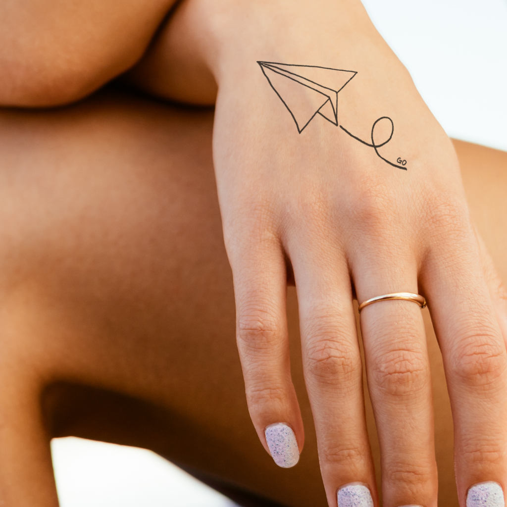 Paper plane tattoo on the inner forearm.
